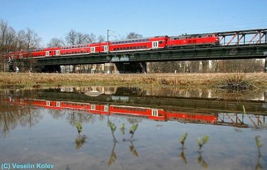 Am 28.03.2009 passiert eine Lokomotive der Reihe 218 mit einem Doppelstockzug
die Braunauer Brücke über die Isar in München. Der Zug ist nach Mühldorf
unterwegs. Für die Spiegelung nutze der Fotograf eine Pfütze mitten auf der
Wiese.