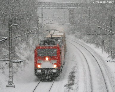 Durch die verschneite bayerische Landeshauptstadt ist eine Lok der Reihe 185 am 21.12.2009 mit einem Containerzug unterwegs. Die Aufnahme entstand am Nockherberg zwischen München Hbf und München Ost.