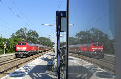 218 457 spiegelt sich am 25.05.2011 bei der Durchfahrt des Haltepunkts Eichenau.