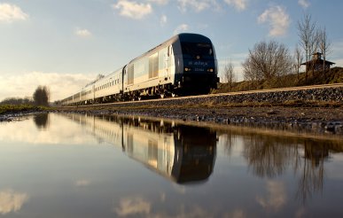 Ein ALEX-Zug spiegelt sich in einer Pfütze bei Geltendorf am 29.01.2016.