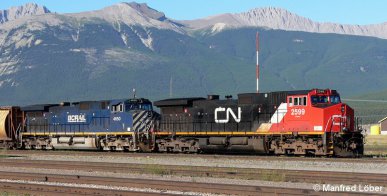 Güterzug fährt nach dem Passieren zweier Kehrtunnels vor der imposanten Kulisse der Rocky Mountains in den Bf Jasper (British-Columbia, Canada) ein.